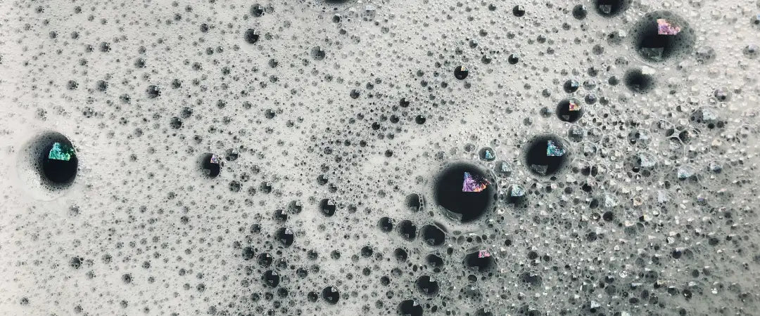 A detailed view of bubbles floating on the surface of a washing basin.
