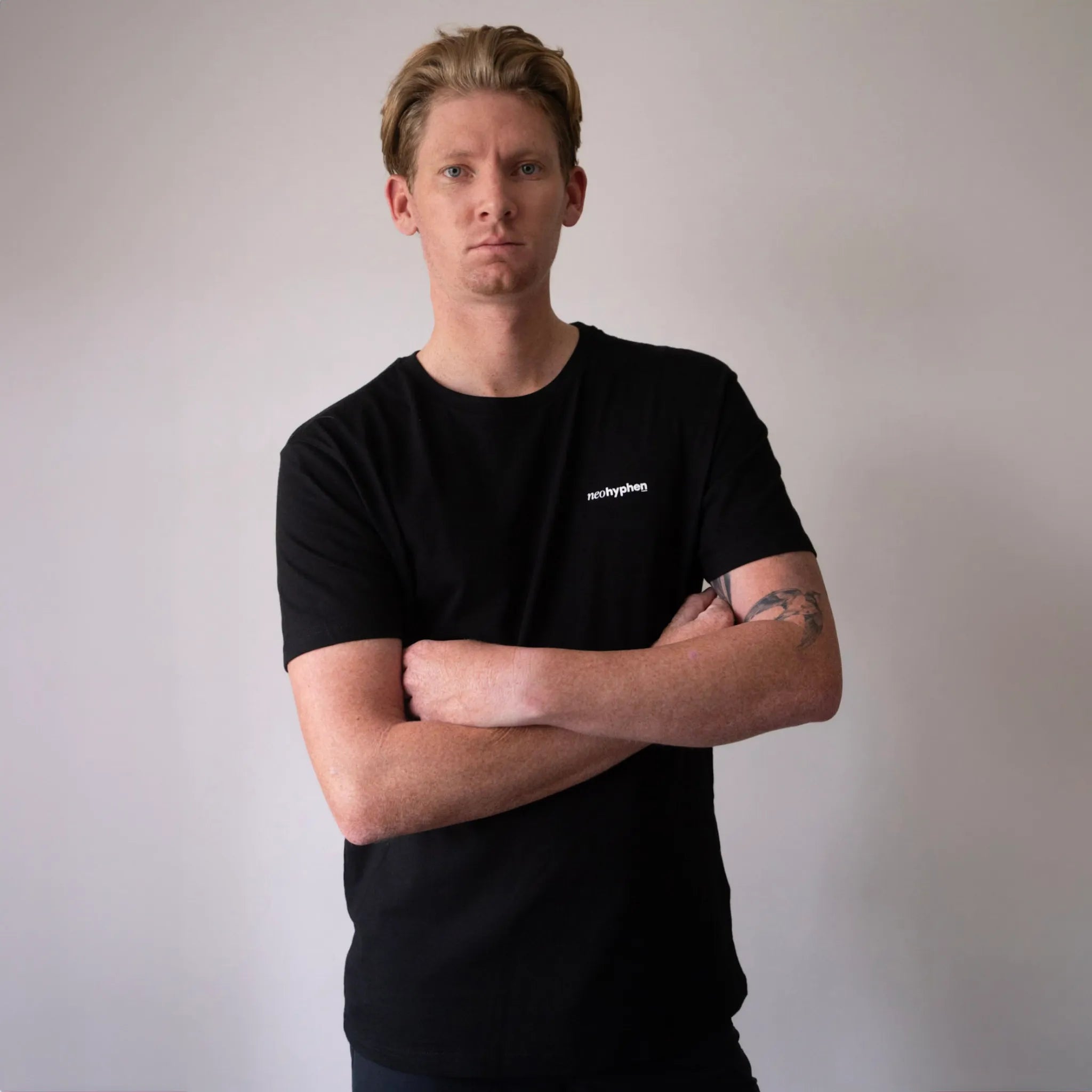 Model wearing Neo Hyphen Speedworks Co. t-shirt, a jet-black 100% organic cotton t-shirt, showcasing a relaxed fit and a streetwear style.