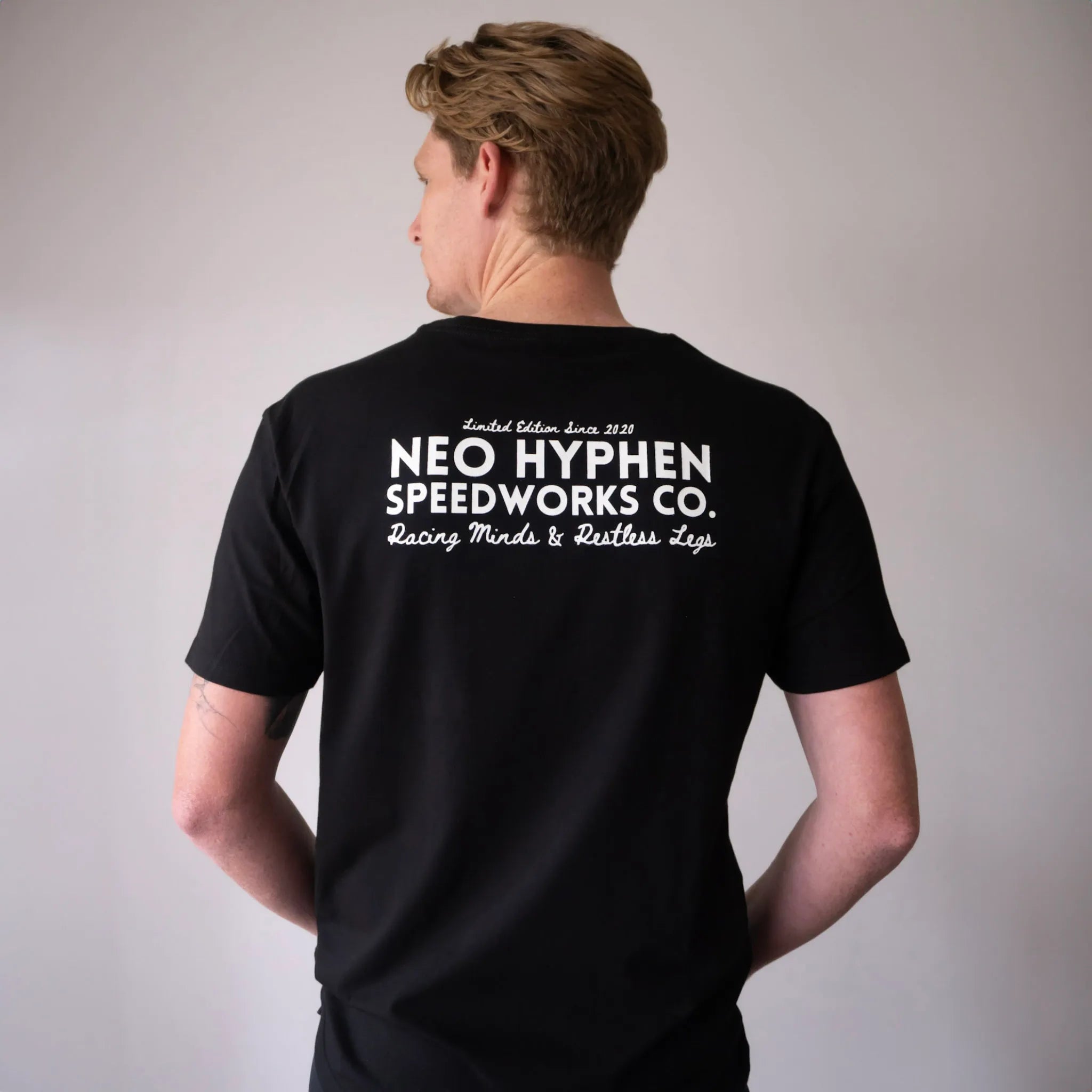 Back view of the Neo Hyphen Speedworks Co. t-shirt in jet-black, featuring bold white text, made from 100% organic cotton for street style.