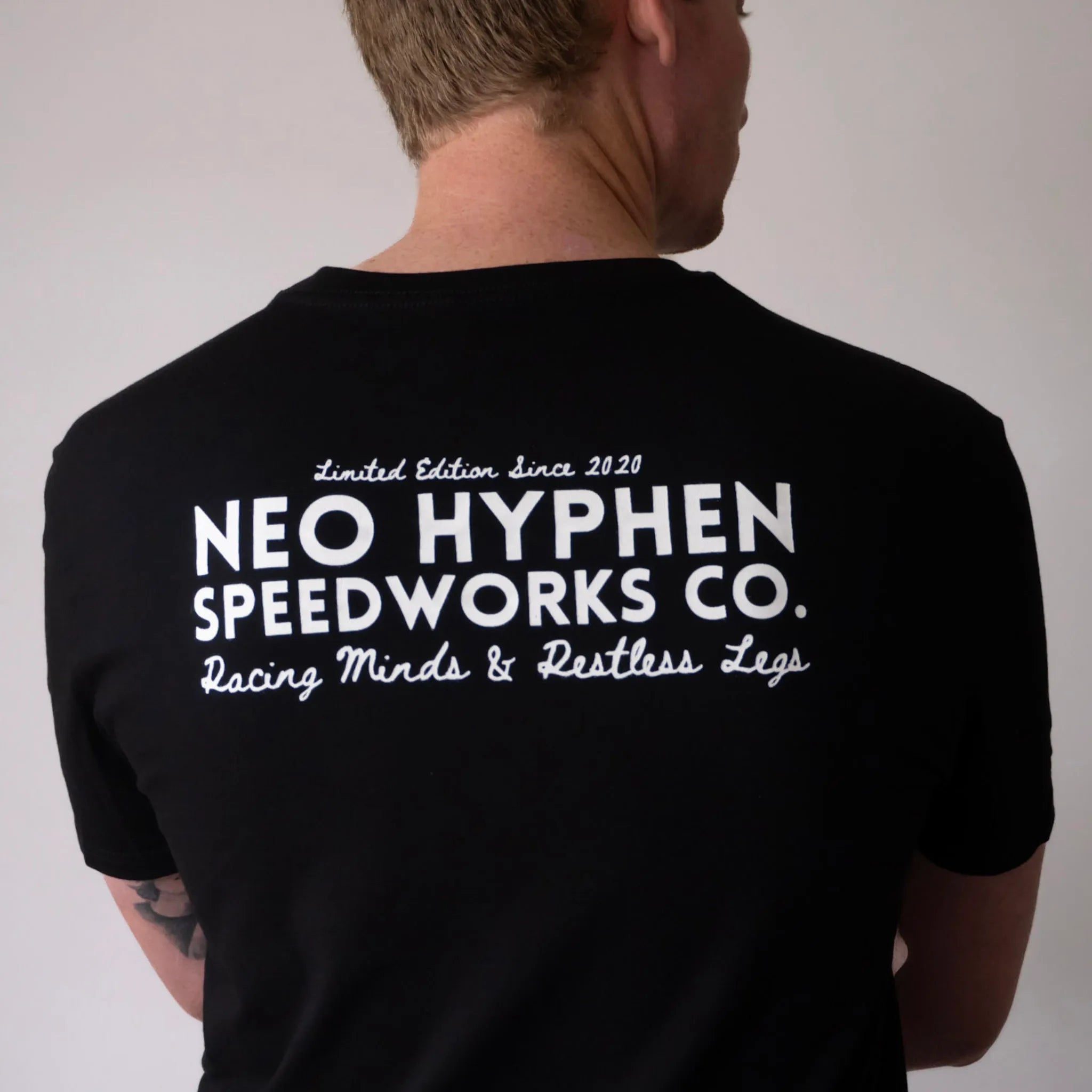 Back view of the Neo Hyphen Speedworks Co. t-shirt in jet-black, featuring with text, made from 100% organic 180gsm cotton.