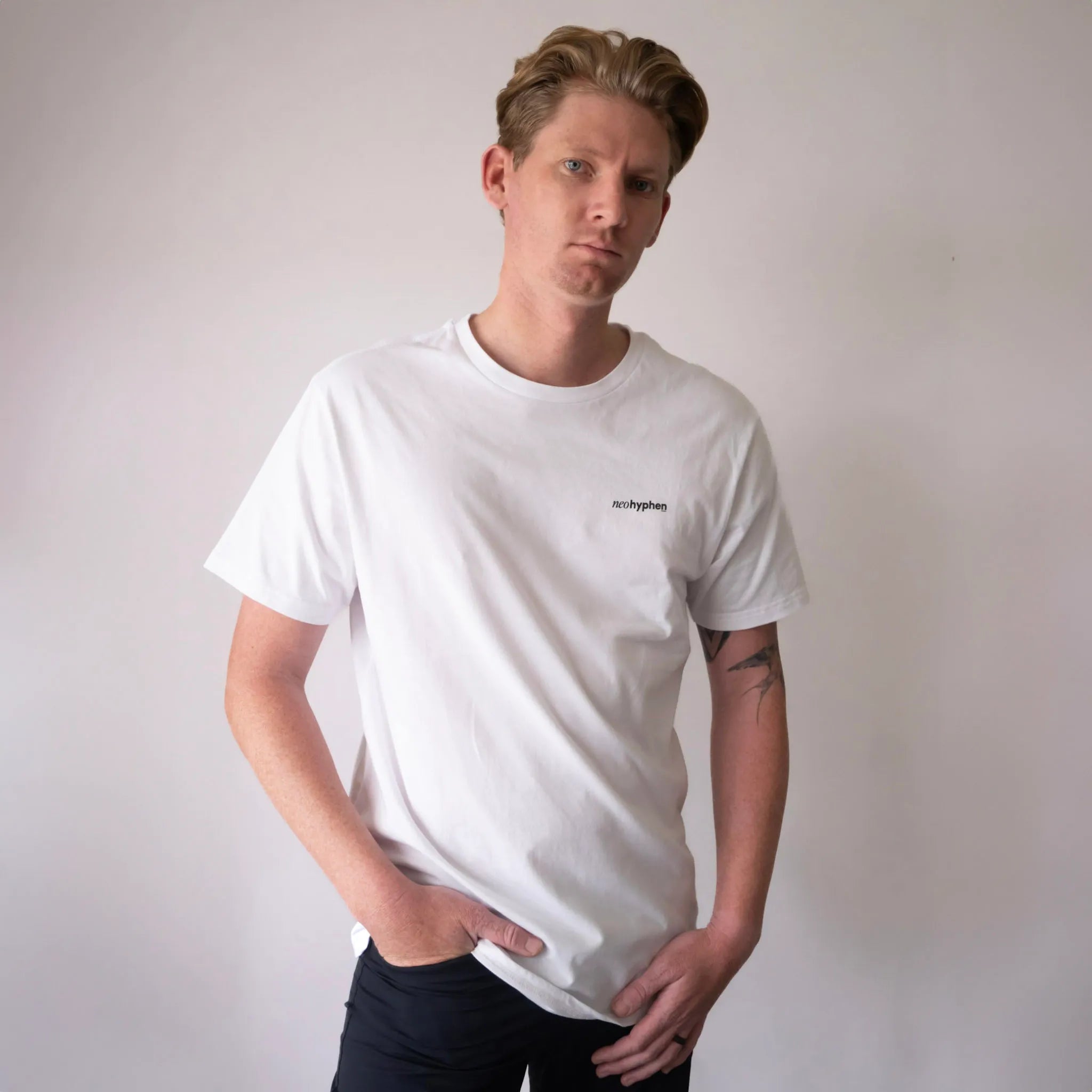 Model wearing a white Neo Hyphen Syndicate of Underdogs Tee made from 100% organic cotton, showcasing relaxed fit street style.