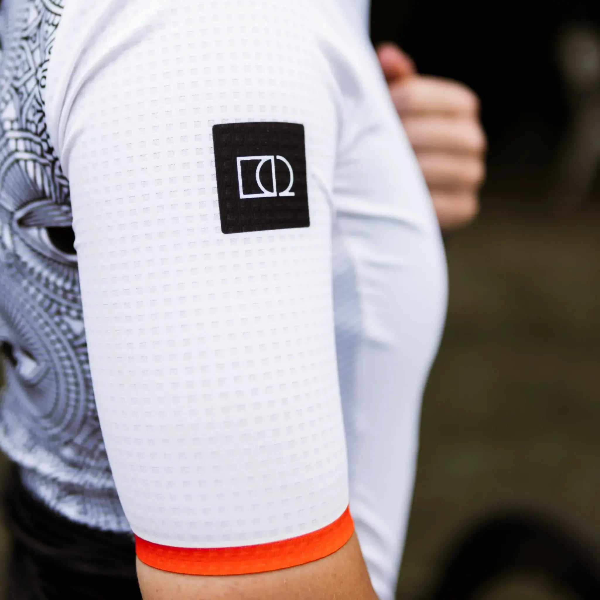 Close-up image of a woman in a All-Seeing Eye cycling jersey, showcasing the Neo Hyphen icon.
